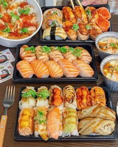 several trays of sushi and other foods on a table