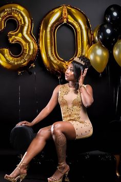 a woman sitting in front of balloons with the number 30 on her chest and wearing heels