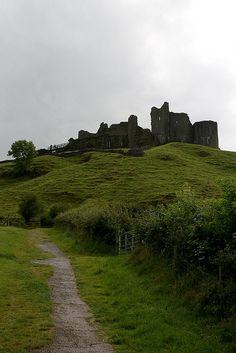 an old castle on top of a hill with a path going up it's side