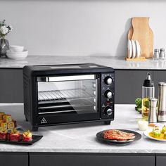 a black toaster oven sitting on top of a counter next to plates and cups