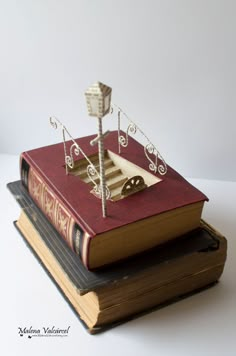 two books stacked on top of each other with a miniature boat sitting on top of them