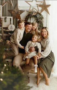 a family posing for a christmas photo in front of a tree with stars on it