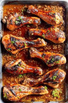 chicken legs covered in sauce and garnished with parsley on a baking sheet