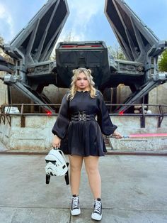 a woman standing in front of a large metal object with her hands on her hips