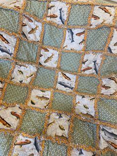 a quilt with birds on it sitting on top of a tablecloth covered in green and orange squares