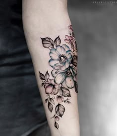 a woman's arm with flowers and leaves on it