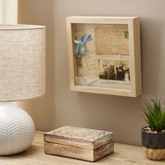 a wooden box sitting on top of a table next to a lamp and a vase