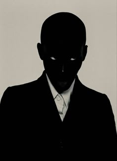 the silhouette of a man in a suit and tie with his face obscured by a shadow