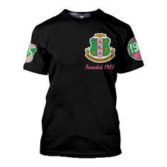 a black t - shirt with pink and green letters on the chest, featuring an emblem for