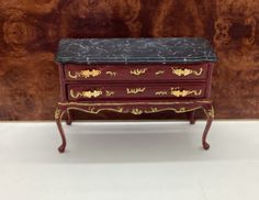 a small red and black dresser with marble top