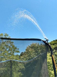 an airplane is flying through the air over a mesh net with trees in the background