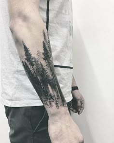 a man with a forest tattoo on his arm