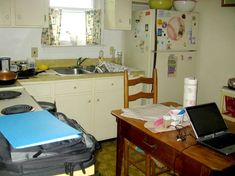 a laptop computer sitting on top of a wooden table next to a kitchen sink and stove