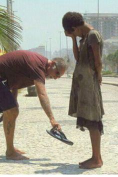 a man bending over to touch another man's shoe