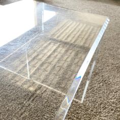 a clear glass table sitting on top of a carpeted floor