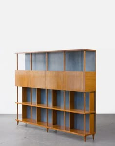 a wooden bookcase with glass doors on the top and bottom shelves, against a white wall