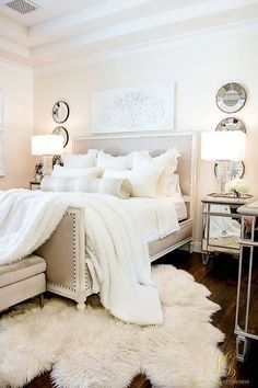 a white bedroom with fur rugs on the floor and bed in front of it