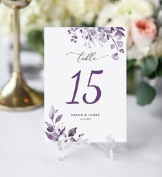 the table numbers are placed on top of each other and have purple flowers in them