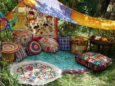 an outdoor area with many colorful pillows and rugs on the ground in front of trees