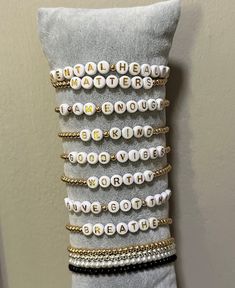 a stack of bracelets sitting on top of a white pillow next to a wall