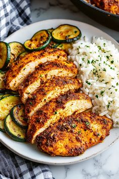 a plate with chicken, rice and zucchini on it