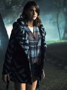 a woman walking in the woods at night with her hand on her hip and looking off into the distance