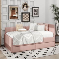 a pink daybed in a white room with framed pictures on the wall and floor