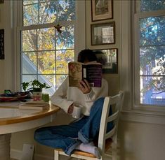 a woman sitting at a table reading a book