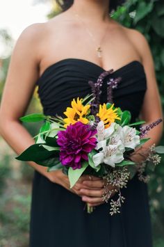 a woman in a black dress holding a bouquet of flowers