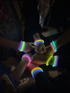 several people are holding their hands together with neon bracelets