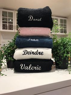 towels stacked on top of each other in front of potted plants and kitchen cabinets