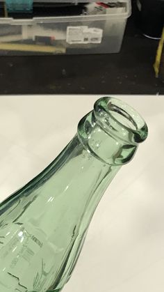 an empty green glass bottle sitting on top of a white tablecloth covered countertop