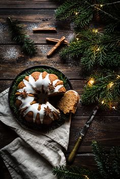 a bundt cake with white icing on a black plate next to christmas decorations