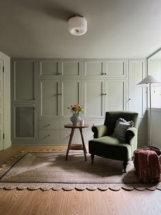 a green chair sitting on top of a hard wood floor next to a table and lamp