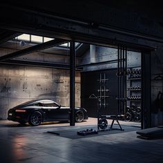 a black sports car parked in a garage next to an exercise station with equipment on the floor