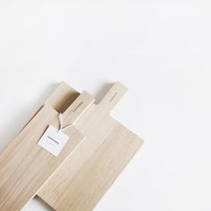 a wooden cutting board with a tag on it sitting on top of a white surface