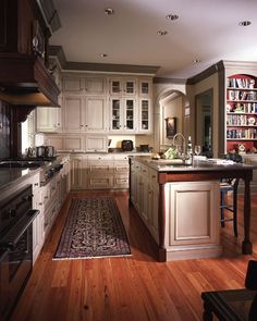 a large kitchen with wooden floors and white cabinetry, along with an area rug on the floor