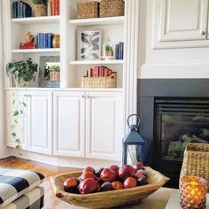 a bowl filled with fruit sitting on top of a table next to a fire place