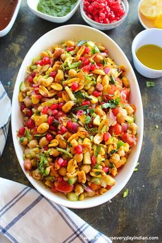 a white bowl filled with beans and veggies next to bowls of dipping sauces