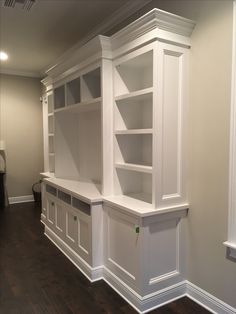 an empty room with white bookcases and wood floors