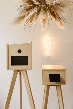 two wooden stands with lights on the wall and one has a bird house in it