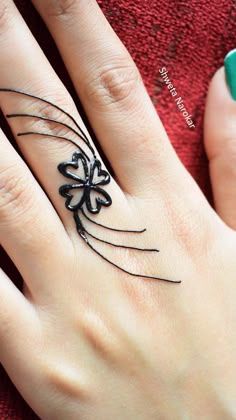 a woman's hand with a tattoo on it and a ring in the shape of a spider