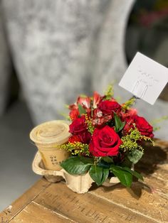 a bouquet of red roses sitting on top of a wooden table next to a card