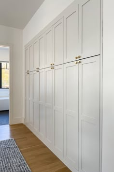 a room with white cabinets and wood flooring next to a large window on the wall