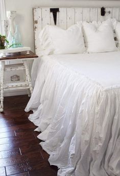 a bed with white ruffled bedspread and pillows