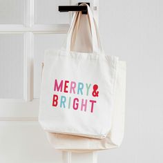 a merry and bright tote bag hanging on a door