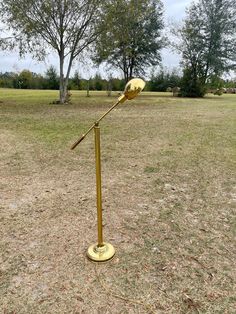 a metal pole with a light on it in the middle of a field