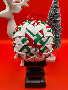 a christmas ornament sitting on top of a stand next to a small tree