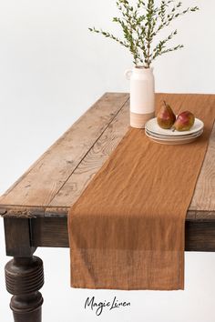 a wooden table topped with a white plate and two pears on top of it