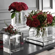 three clear vases with red flowers in them